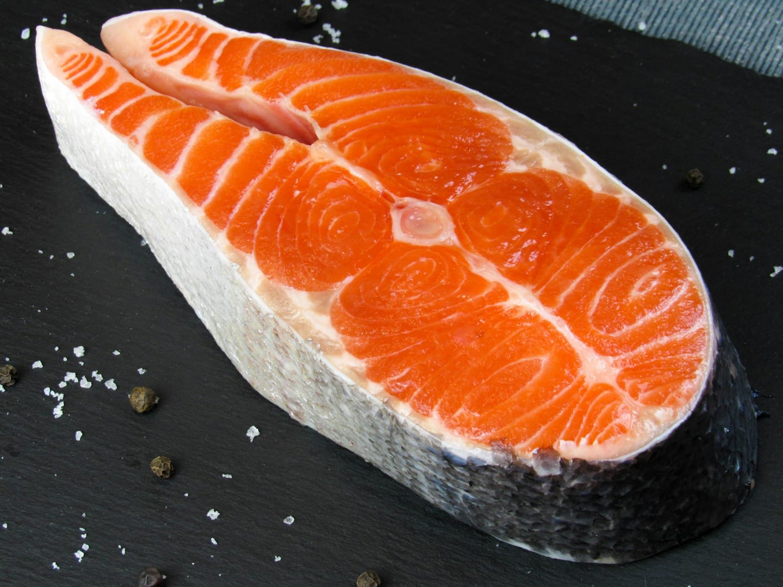 A raw salmon fillet on a dark table