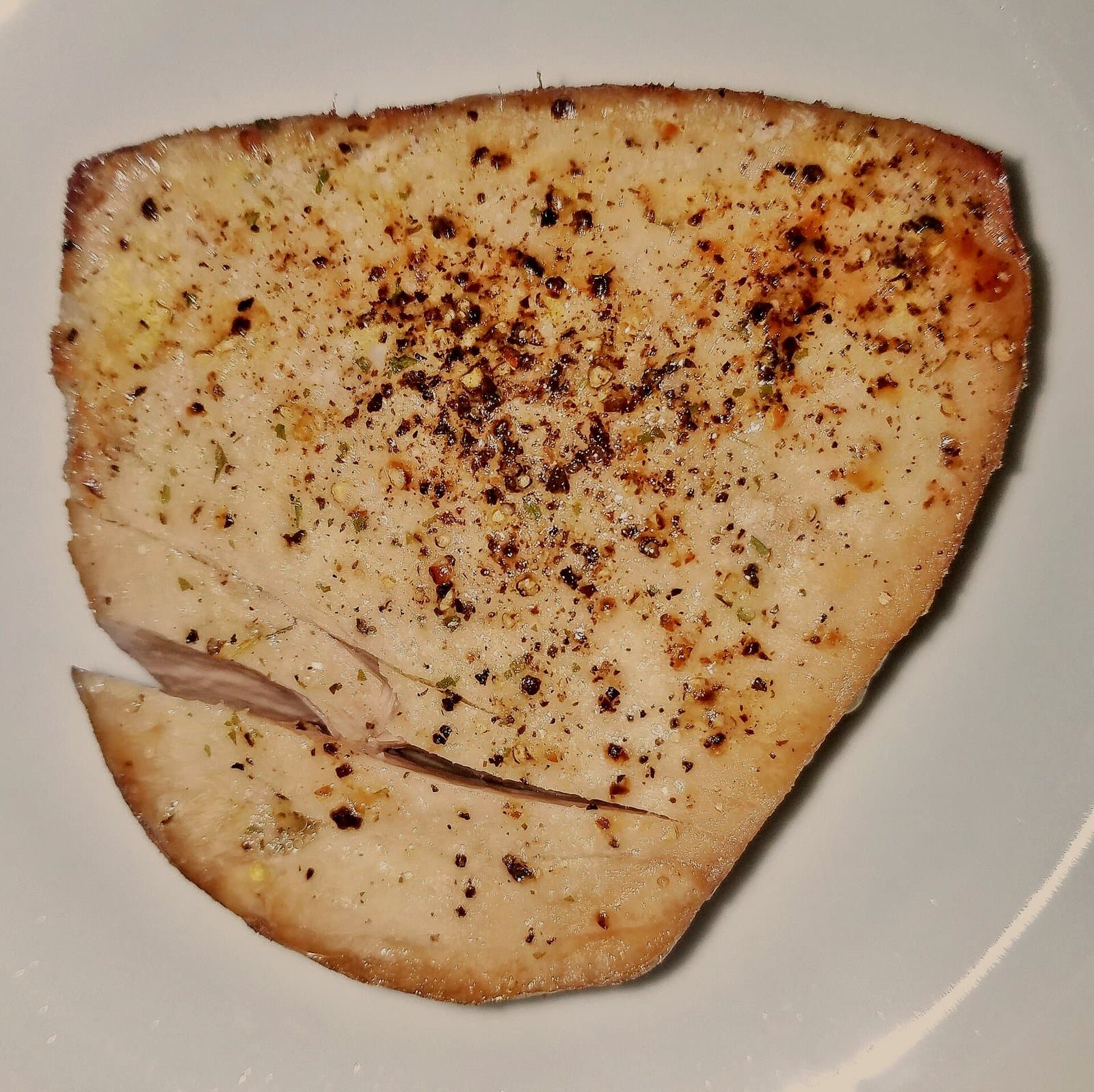 A raw tuna steak with olive oil and black pepper